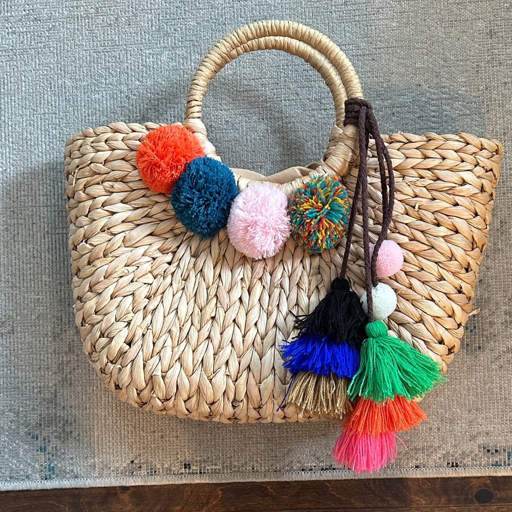 Colorful Pom-Pom Straw Tote Bag with Drawstring Closure on Inside.
